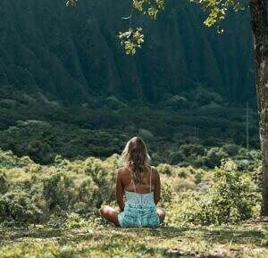 woman sitting on a hillside looking at other hills.