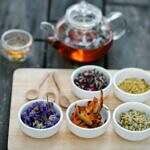 A tray of herbs on a table with a teapot and cup.