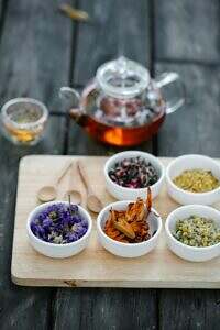 A tray of herbs on a table with a teapot and cup.