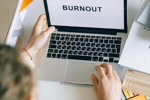 person looking at laptop with the word burnout on the screen.