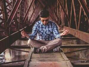 Man sitting on a steel beam meditating.