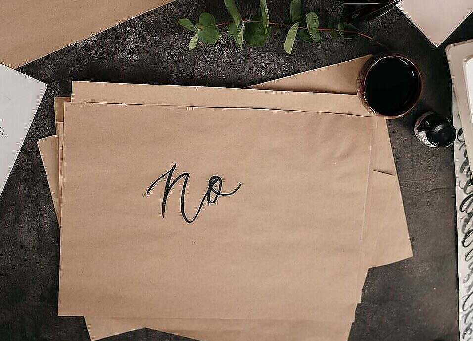 the importance of a "no" person in your life. Image of brown paper on a desk with the word no written in script.