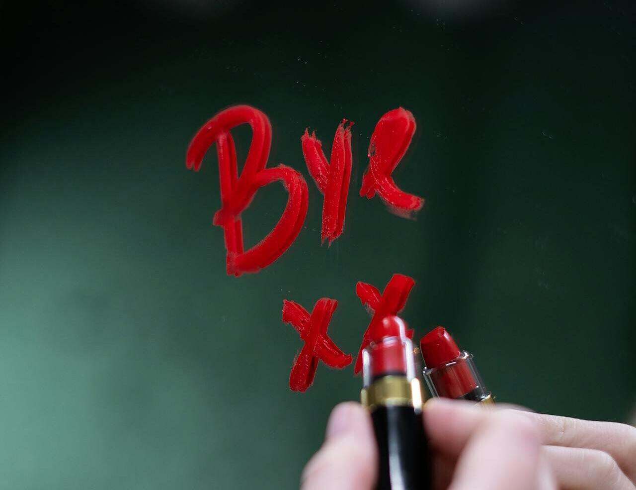 Image of a mirror with a person writing in red lipstick Bye xx. Represents losing people...