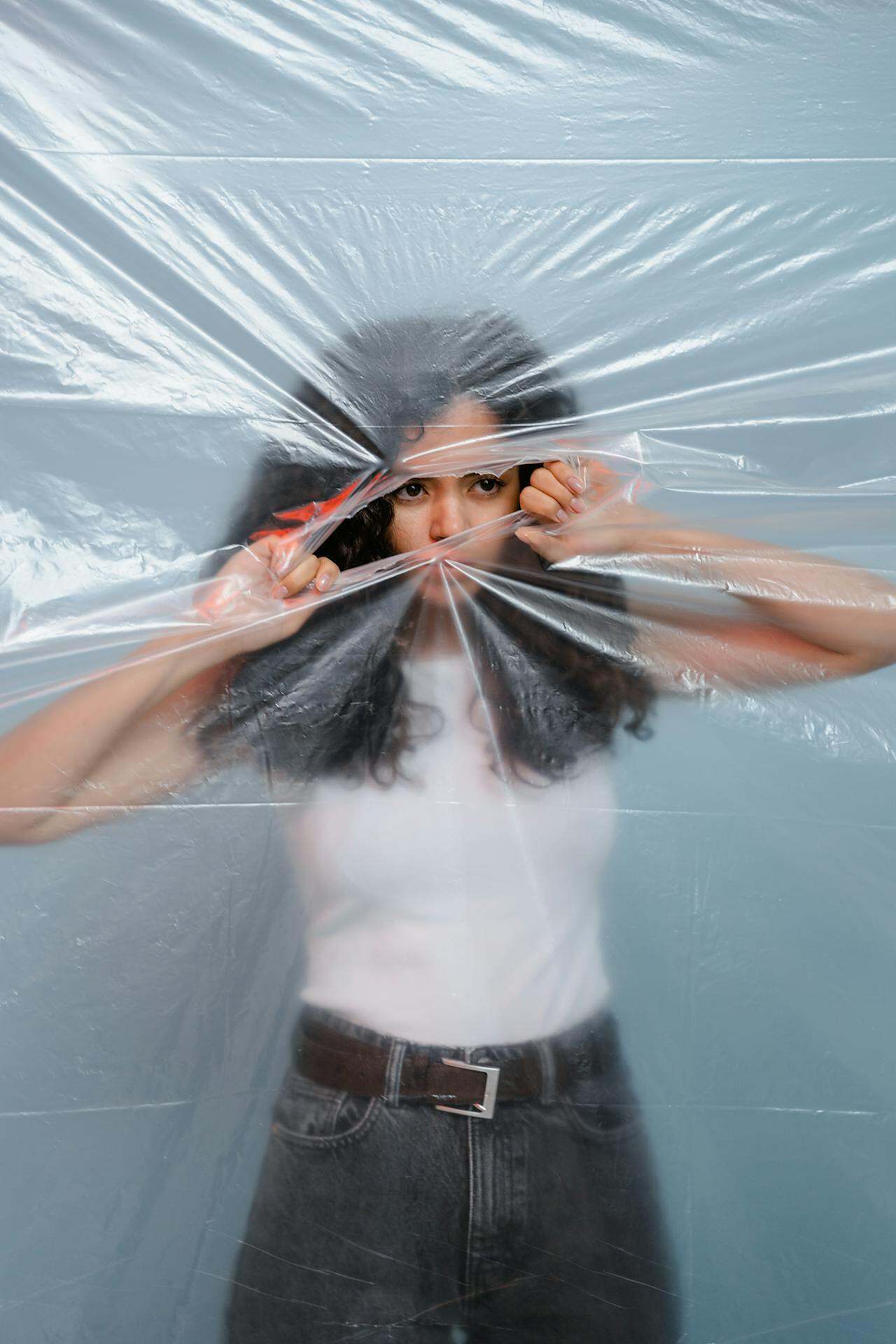 Awakening Through Loss: When Death—or Any Ending—Opens the Door to Spiritual Growth Image of a women behind plastic ripping it open.