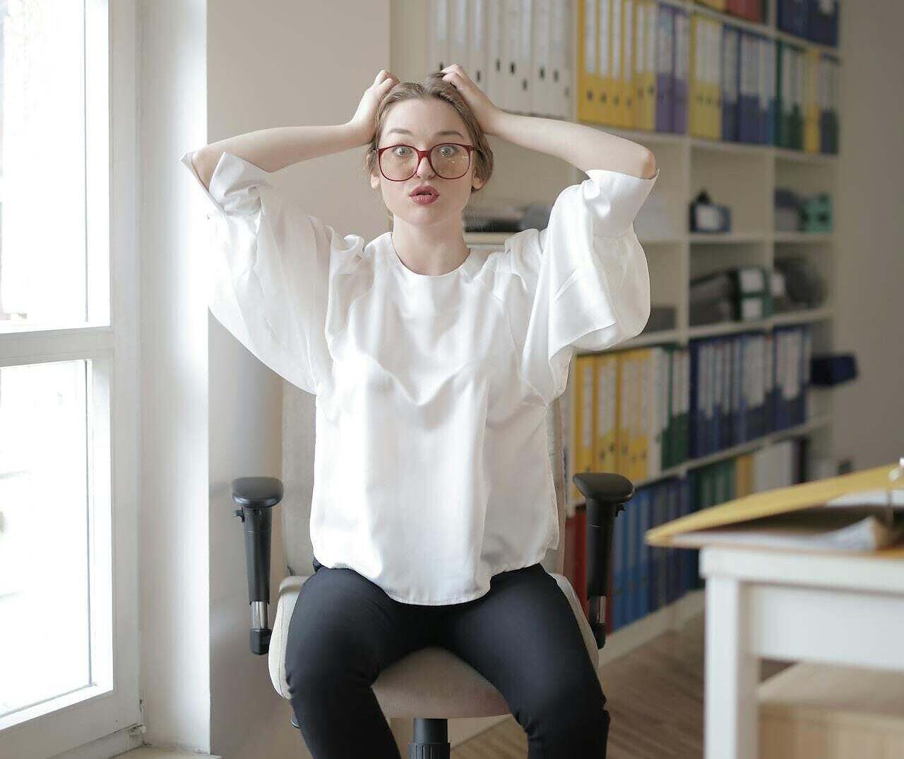 Not every spiritual teacher is meant to stay in our lives forever. Some—whether they realize it or not—show up to teach us what not to do. Image of a woman at a desk in front of a window looking stressed out
