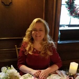 Image of Rev. Colleen Irwin sitting at a table with a selection of metaphsyical tools on the table.