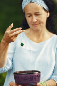Image of a woman holding a pendulum and a singing bowl.