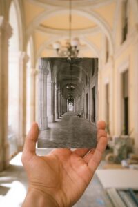 Image of a photograph of a building in the past with the current view behind it.
