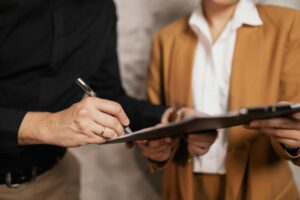 Image of a woman holding a clipboard while a man signs