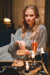 Image of a woman holding tarot cards with a glass of wine in front of her.
