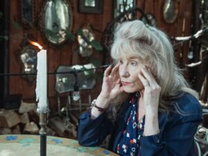 Image of an older woman holding her head focusing on a candle.