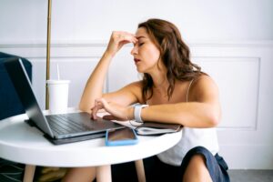 Image of a woman sitting at a laptop looking exhausted.