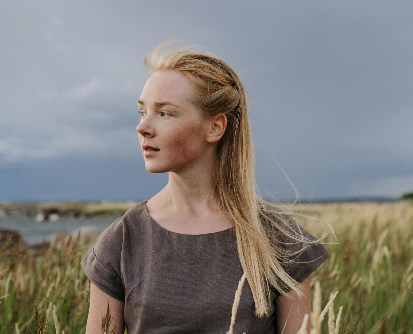 Image of a woman standing in a field looking off into the distance.
