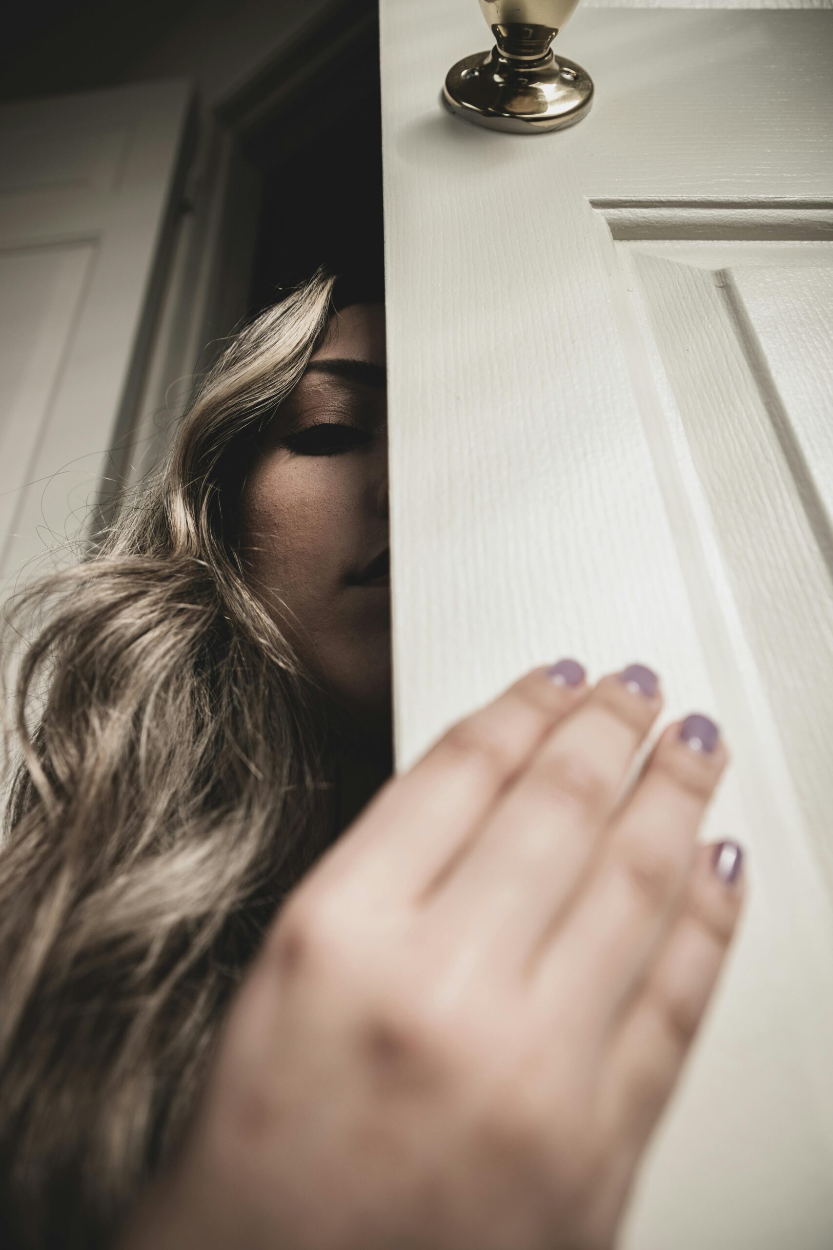 Image of a woman opening a door sheepishly.