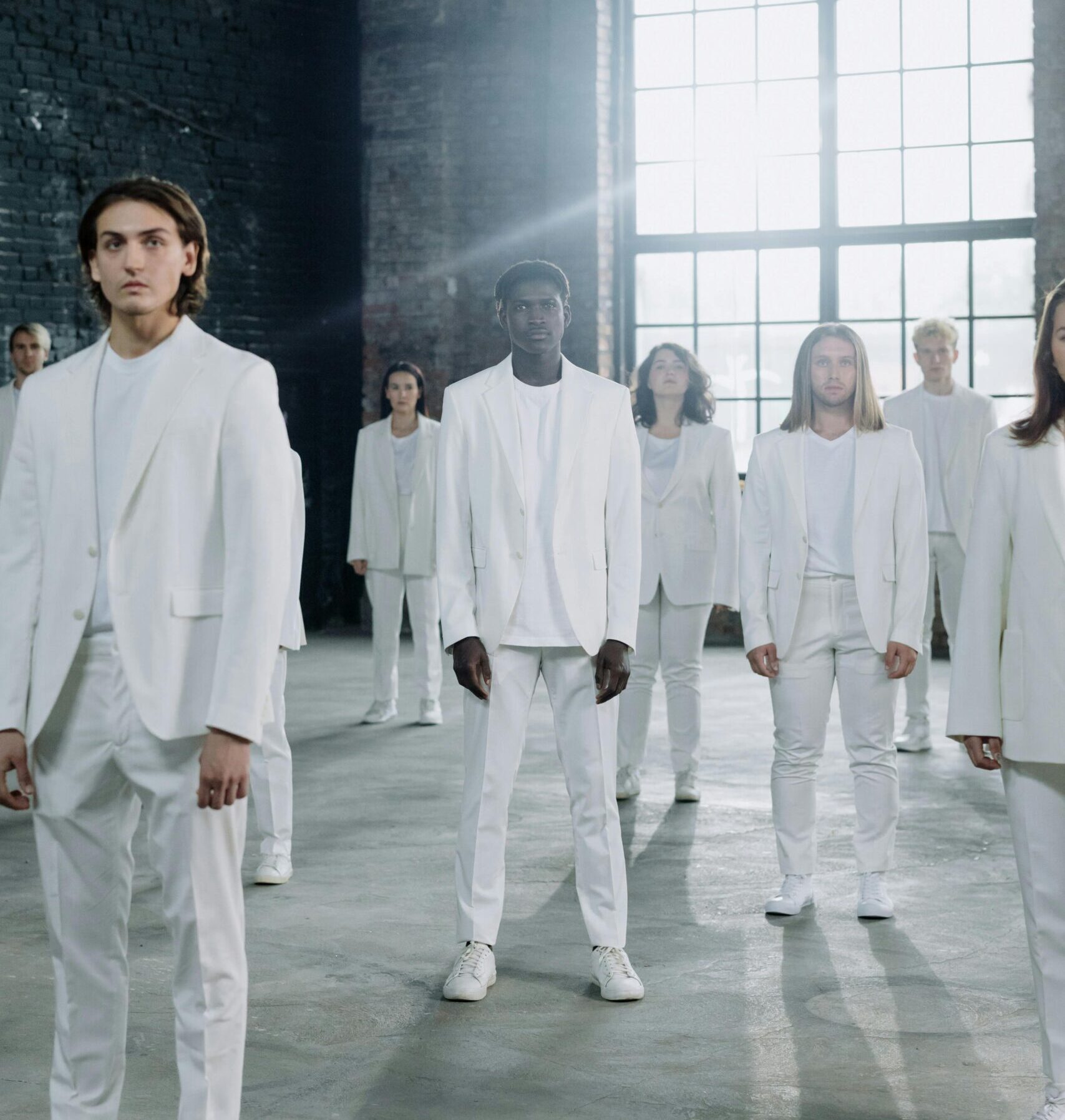 Image of a diverse group of people all dressed the same with a ray of sunshine streaming in the windows behind them.