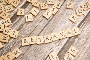 Image of scrabble tiles spelling out betrayal out.