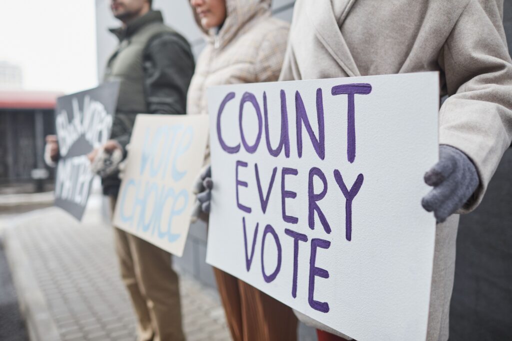 Image of people holding signs one that says count every vote