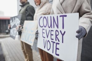 Image of people holding signs one that says count every vote