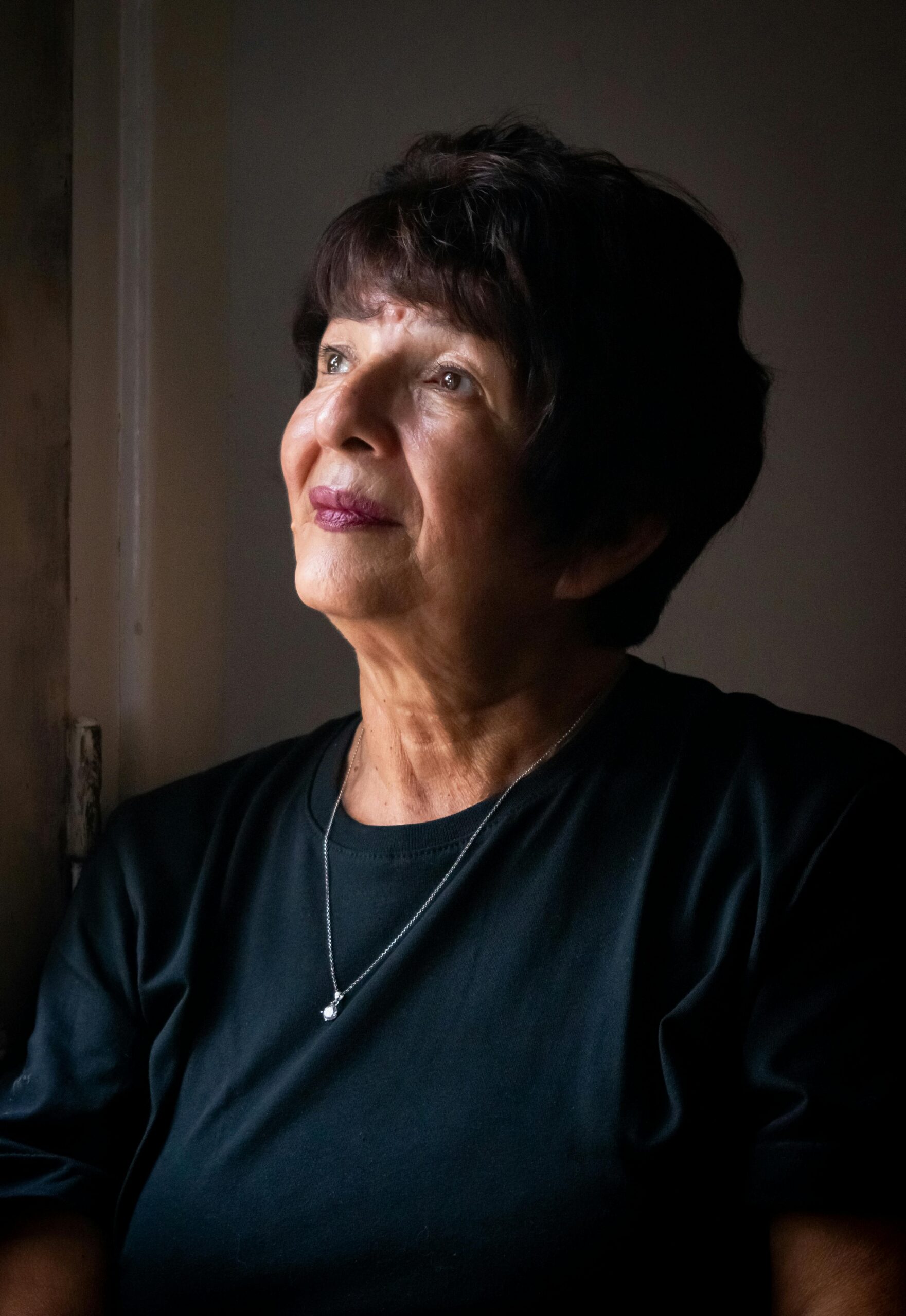 Image of a women sitting at a window looking out thoughtfully.