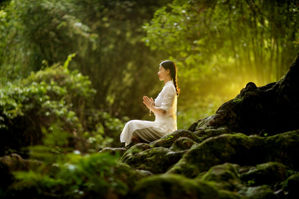 Image of a woman meditating in the middle of a forest.