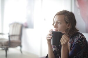 Image of a woman holding a cup of tea looking off into the distance.
