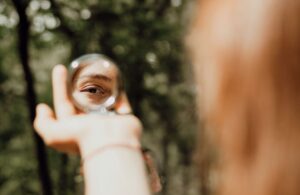 Image of a woman looking into a mirror in her hand