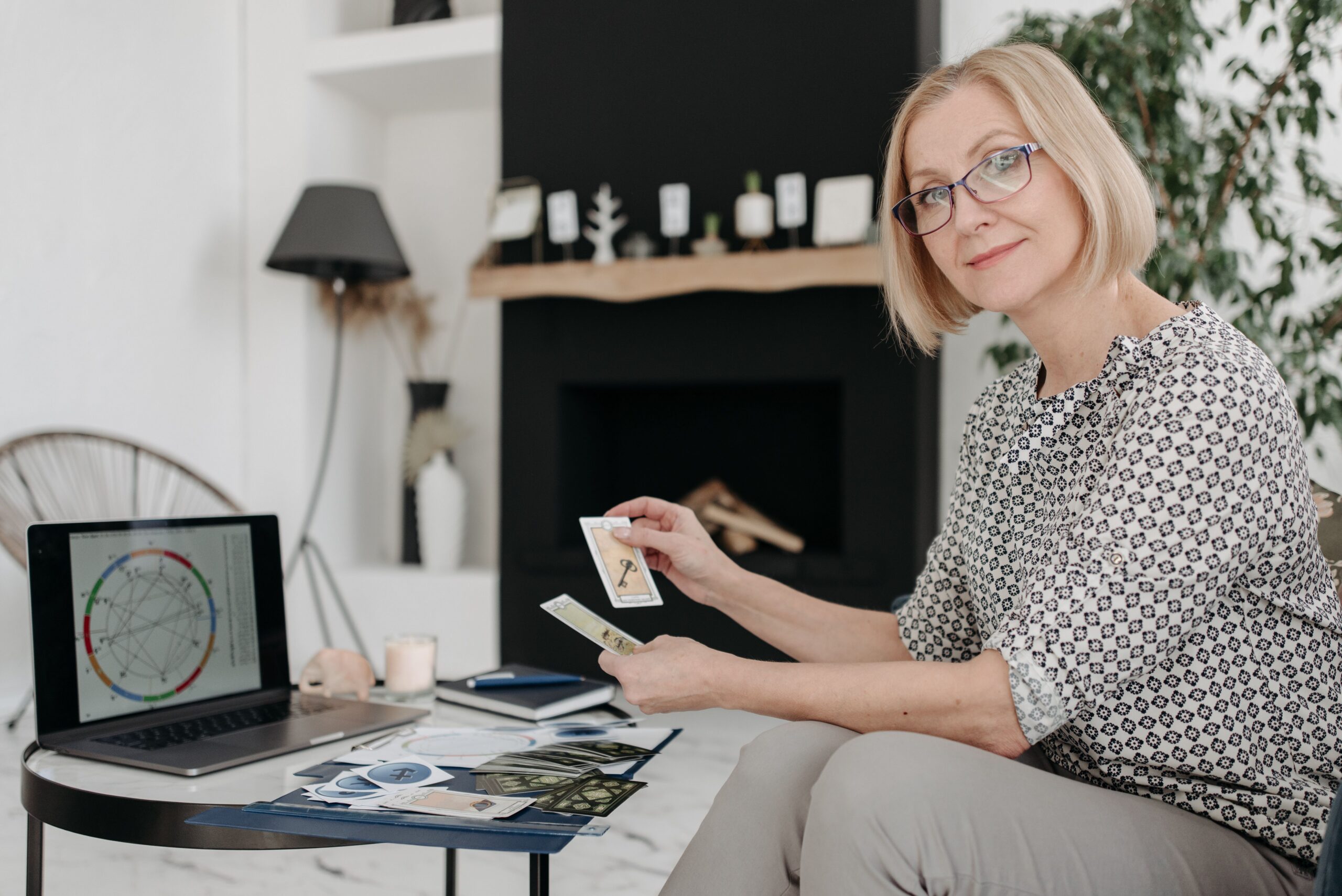 Image of a woman sitting with a deck of tarot cards looking into the camera.