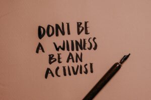 Image of writing on a piece of paper that says: Don't be a witness, be an activist"