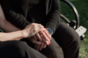 Image of two women sitting on a bench holding hands.