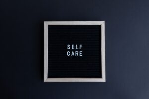 Image of a sign with the words self care on it in white letters.