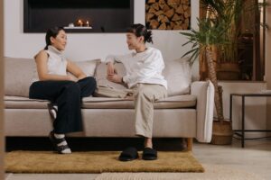 Image of two women sitting on a couch engaged in a conversation.